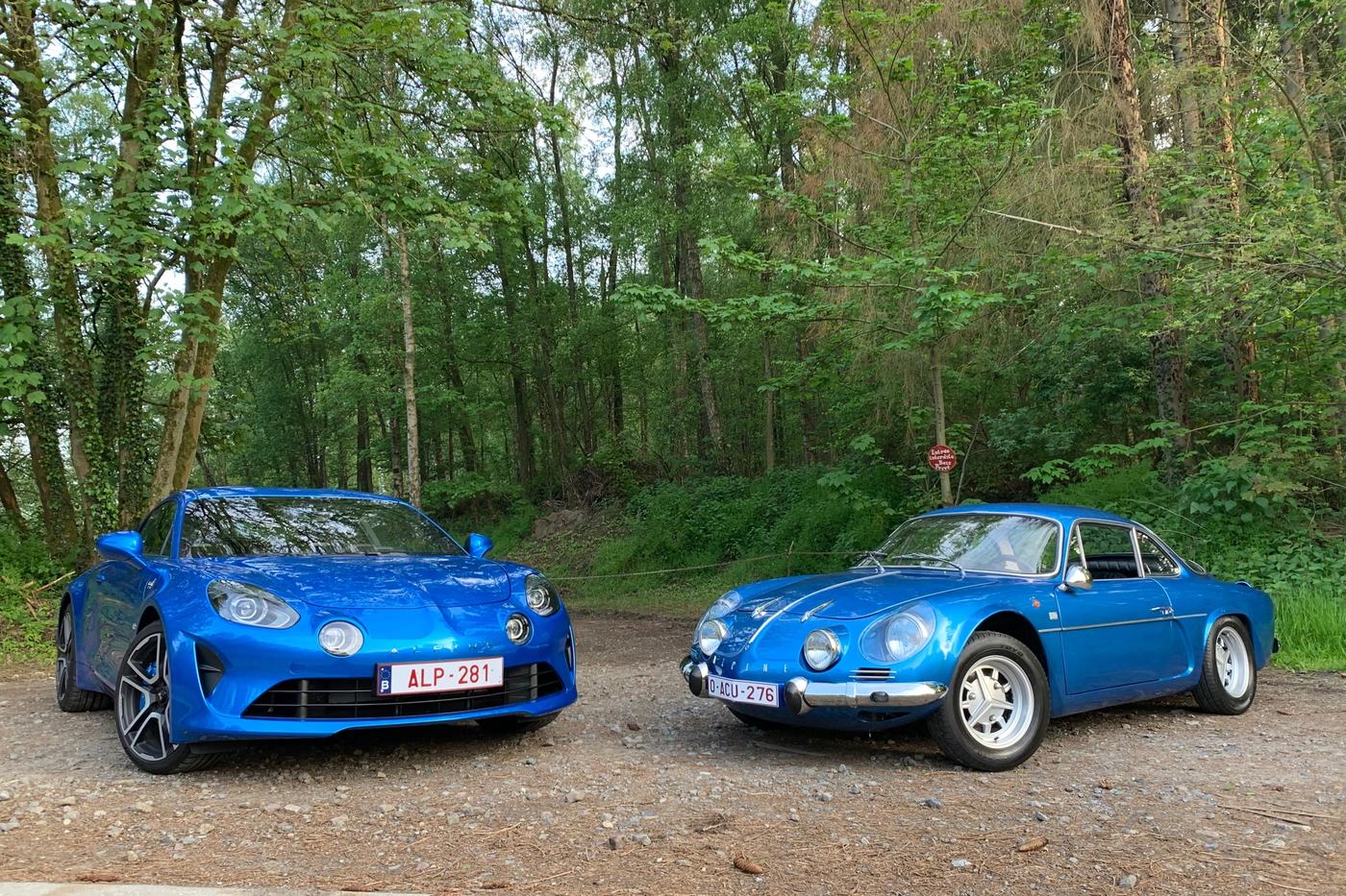 Alpine A110 de 2018 aux côtés d’une Alpine A110 berlinette d’origine, toutes deux bleues, en forêt