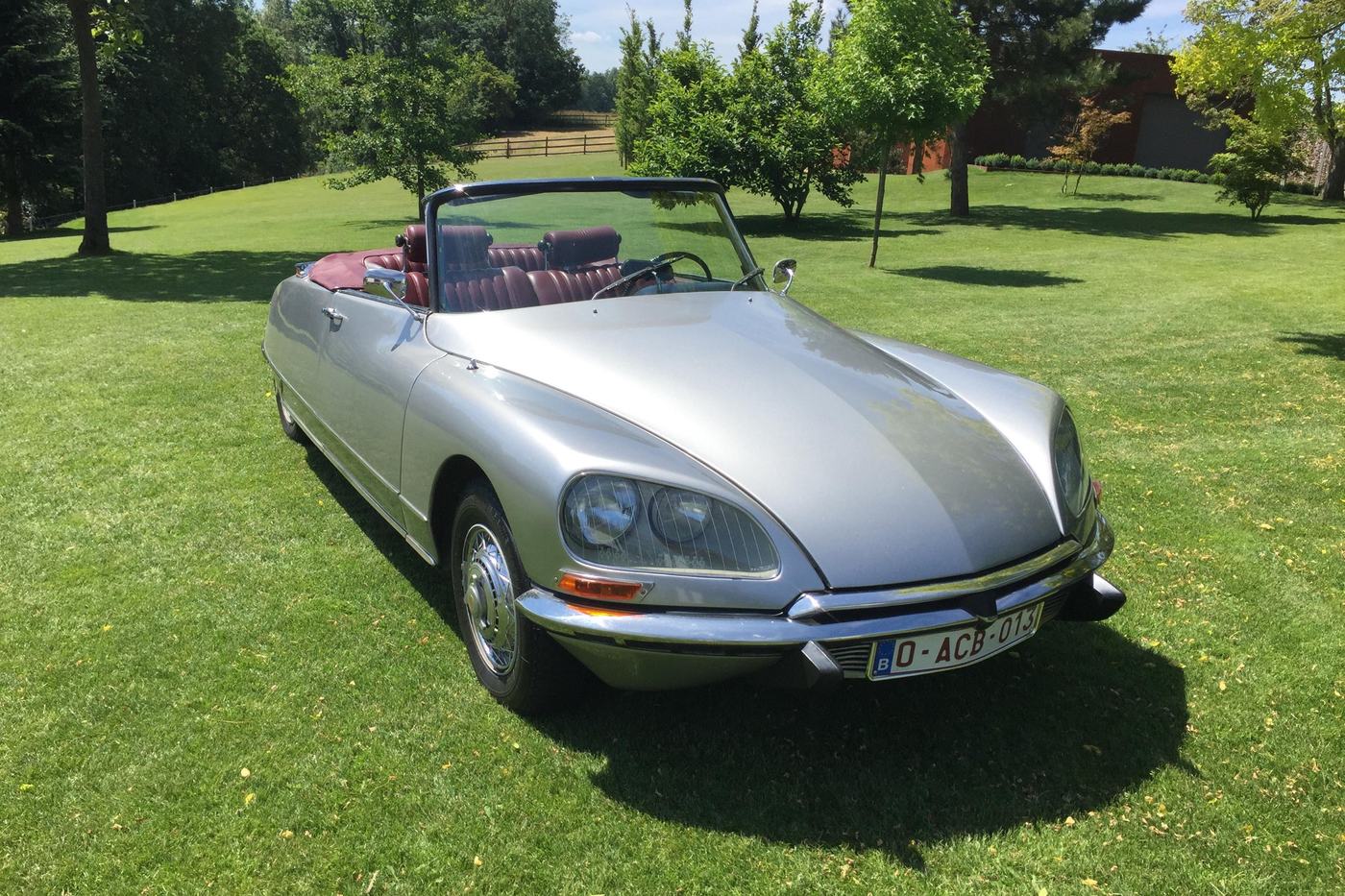 Citroën DS 21 cabriolet gris métallisé de 1969, capote baissée, vue de trois quarts avant sur une pelouse
