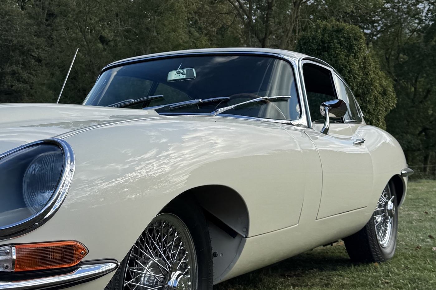Jaguar Type E coupé blanc cassé de 1963 vue de trois quarts avant, roues à rayons, sur l’herbe