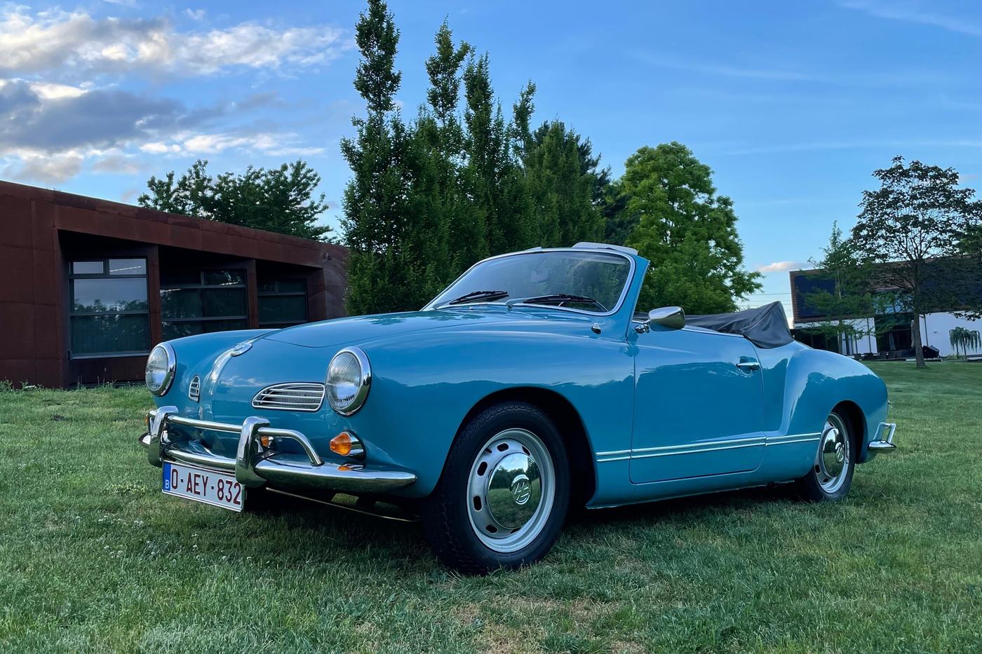 Volkswagen Karmann Ghia cabriolet bleu clair de 1968, capote baissée, sur une pelouse en fin de journée