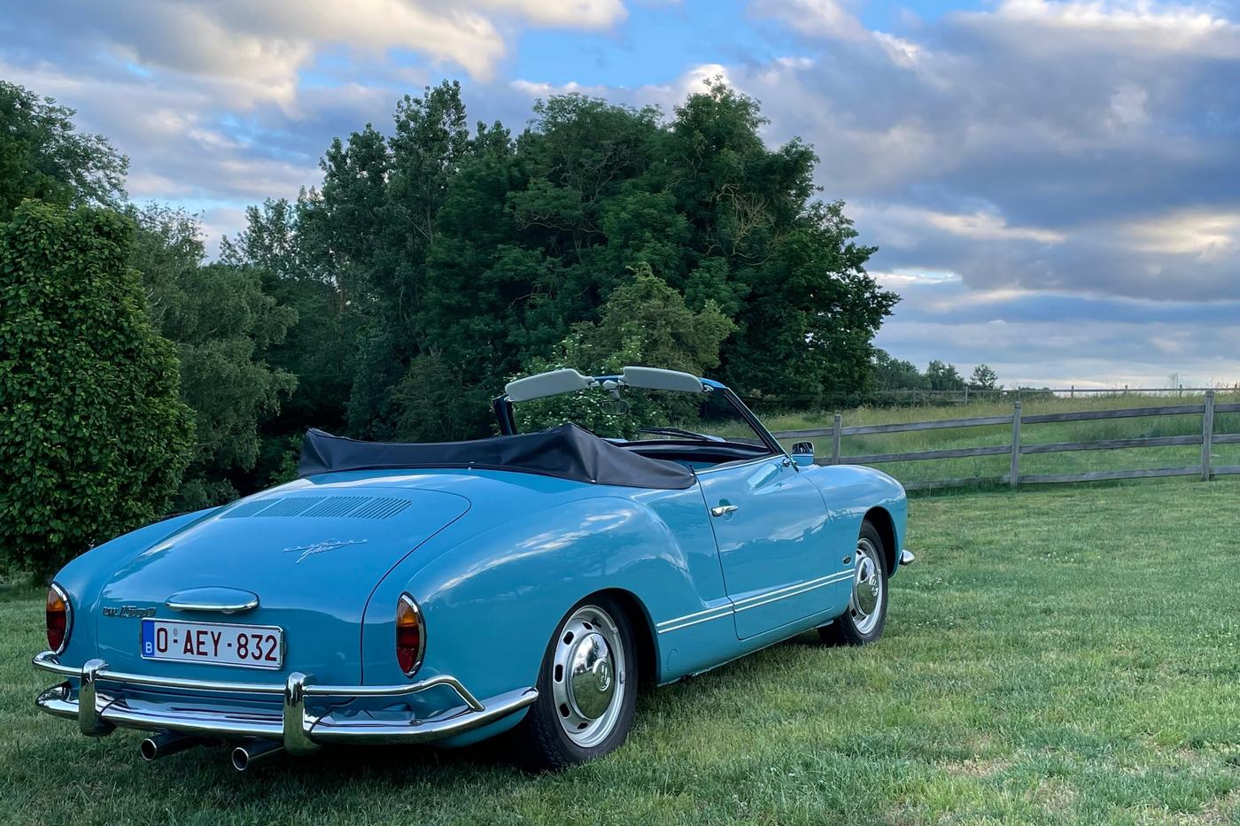 Volkswagen Karmann Ghia cabriolet bleu clair vue de trois quarts arrière, sous un ciel nuageux