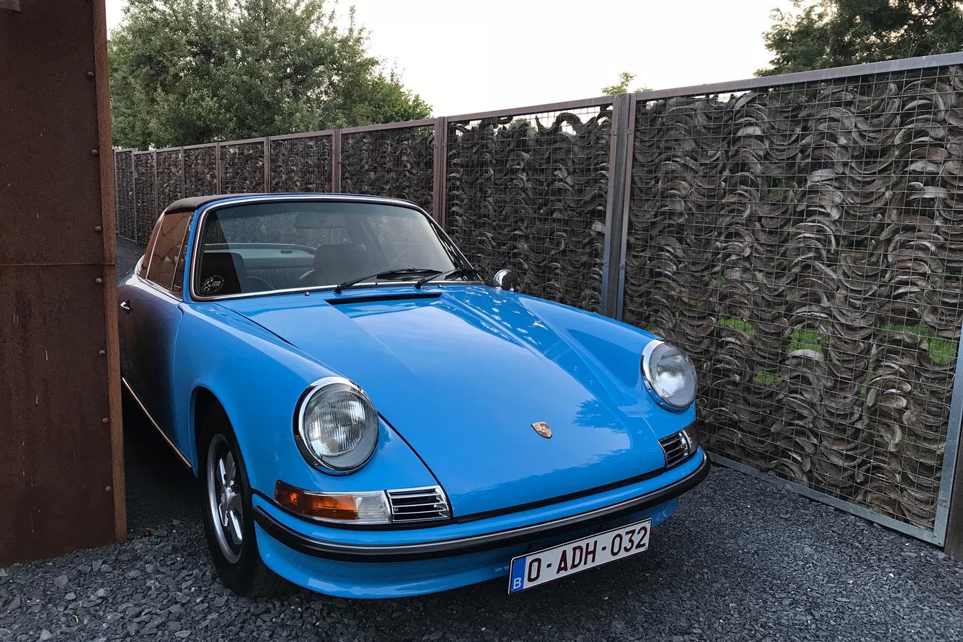 Porsche 911 E Targa bleu clair de 1970 vue de trois quarts avant dans une cour