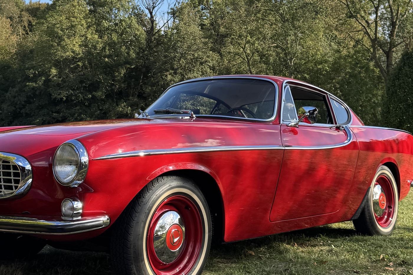 Volvo P1800 rouge de 1964 vue de trois quarts avant, jantes rouges et enjoliveurs chromés